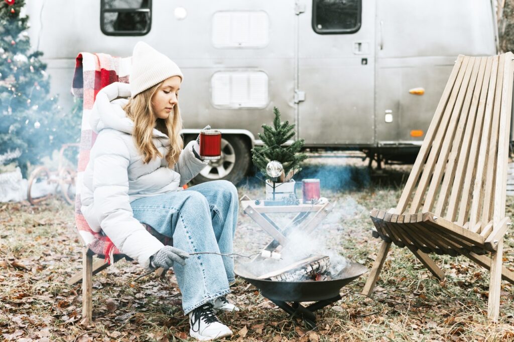 Young woman dressed in winter clothes sits in front of RV-RV storage units